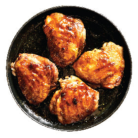 Just Bare Bone-In Thighs shown roasted in a cast-iron skillet and ready to be served.
