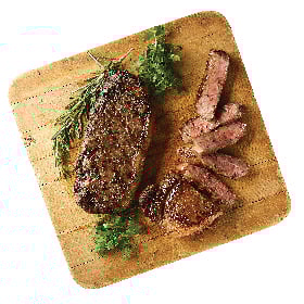 Two Bone-In Strip Steaks from Dierbergs Butcher Shop shown cooked and resting on a wooden board, one cut into slices.